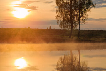 Fototapeta na wymiar Landscape: fog or steam over lake at sunrise