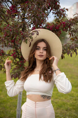 Long-haired girl in a hat in an Apple orchard in spring