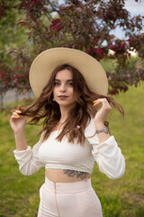 Long-haired girl in a hat in an Apple orchard in spring