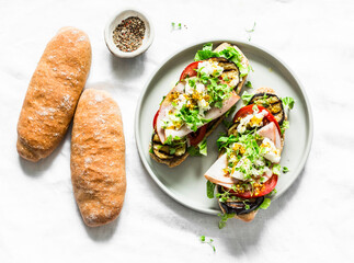 Sandwiches  with grilled eggplant, tomatoes, ham, mozzarella and micro greens on a light background, top view. Delicious sandwiches for appetizers, tapas