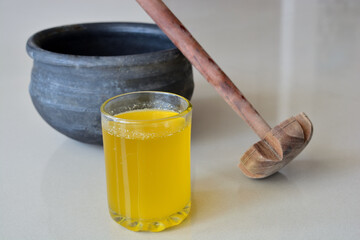 glass of ghee with earthen pot and wooden whisk