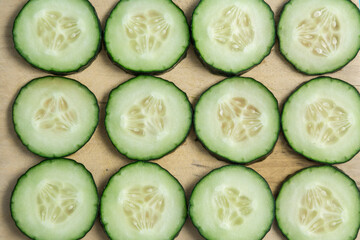 table with cucumber cut into slices, background with vegetables