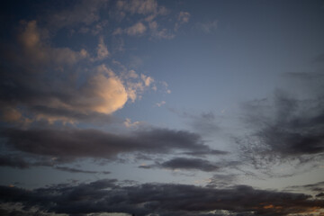 Fototapeta na wymiar evening blue sky with dark clouds lit by the orange sun