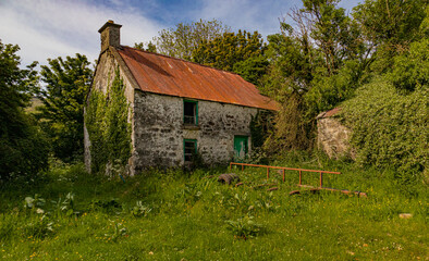 Fototapeta na wymiar Derelict old stone house with rust red tin roof in Carnlough, County Antrim, Northern Ireland