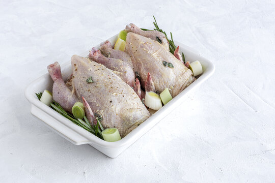 raw coquelet chickens prepared for roasting with vegetables and herbs