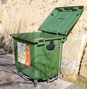 VALLETTA, MALTA - NOVEMBER 10TH 2019: A green rubbish bin stands open near the Valletta bus station. Ghalfejn thammeg pajjizek means Why tarnish your country. skart imhallat means mixed waste.