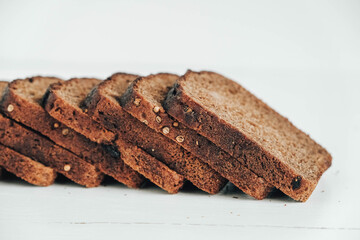 Slices of fresh brown bread with raisins on a white wooden background. Copy, empty space for text