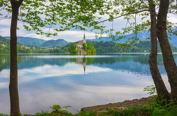 Beautiful morning at Lake Bled and Julian Alps in the background, with natural frame. The lake island and charming little church are famous tourist attraction in Slovenia.