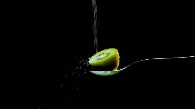 medio kiwi verde visto de cerca rociado con az&uacute;car en c&aacute;mara lenta