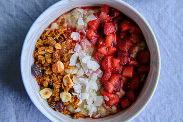 Healthy Vegan Homemade Breakfast. Oatmeal with strawberry sauce, coconut and granola.