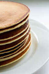 Pancakes on a white plate close-up on a light background