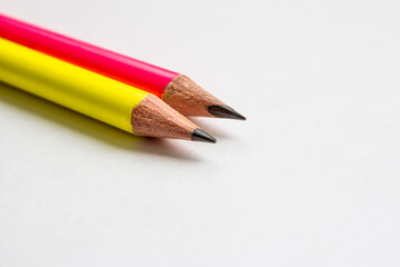 Pink and yellow pencils on a white background