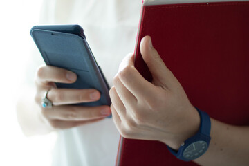 Frau hält rote Datei und Handy in der Hand