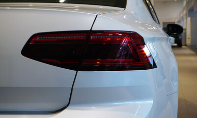 Modern luxury new white car in salon, rear view. Close-up taillight. Auto business, car sales, service and repair. Concept.