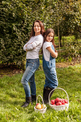 Portrait of little girl and beautiful mother in organic apple orchard happy and having fun.