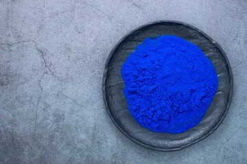 Blue spirulina powder on black stone plate Phycocyanin extract. Natural superfood, vegan, healthy...