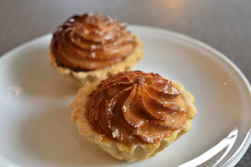 Cake basket with marzipan and marmalade on a white saucer. Baked dough. Makronen tartlets.