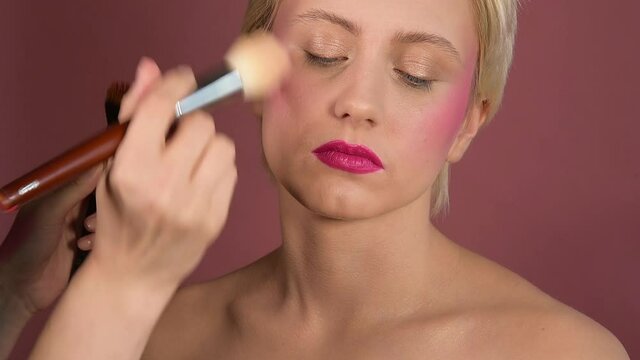professional makeup, makeup artist paints the skin with a brush, hands closeup,