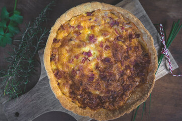 Quiché Lorraine. Bacon and cheese French pie over a Wood chopping board with decoration.