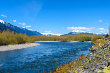Majestic mountain river in winter over snow mountains and blue sky in Vancouver, Canada.