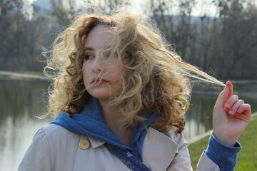 Close up portrait of a youg girl looking to the side. Cute curly girl outdoor. People, travel, nature concept.