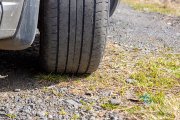 Obraz premium Shabby rubber tire of car wheel on gravel road during a summer trip