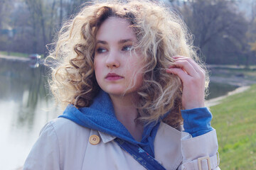 Naklejka premium Close up portrait of a youg girl looking to the side. Cute curly girl outdoor. People, travel, nature concept.