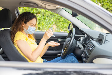 Young woman using hand sanitizer in a car