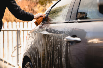 mężczyzna myje ręcznie samochód na swoim podwórku  - obrazy, fototapety, plakaty