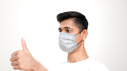 Young Asian boy thumbs up and wearing protective mask against the corona virus covid 19 brown man wearing surgical mask to prevent from virus white background Corona virus pandemic