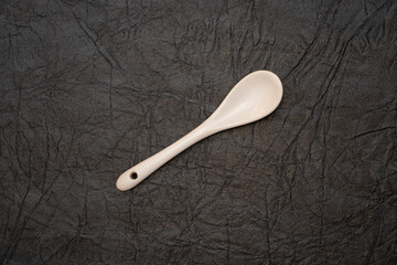 White glazed porcelain coffee spoon on artificial leather background.