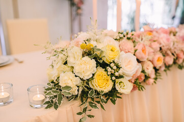 Banquet, restaurant. Table setting. On the table is a pink tablecloth. Presidium, table of the newlyweds. There is a tablecloth on the table. Floral arrangements in peach pink hues. Tall candles