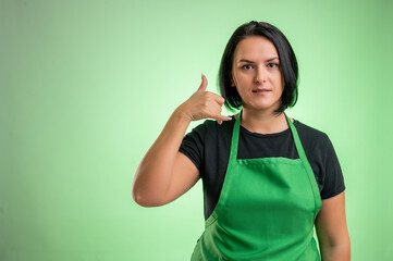 Female cook with green apron and black t-shirt showing call me gesture