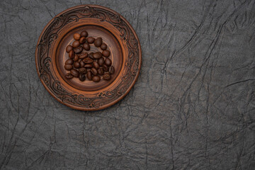 Homemade saucer made of glazed clay. A pinch of brown roasted aromatic coffee beans.