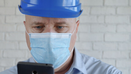 Engineer with Safety Helmet and a Protection Mask on His Face Talking to the Cell Phone