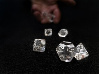 A hand throwing a set of transparent dice on a black surface