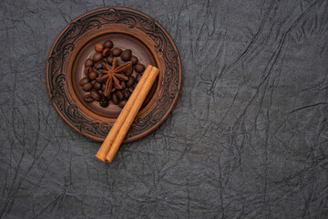 Homemade saucer made of glazed clay. A pinch of brown roasted aromatic coffee beans.