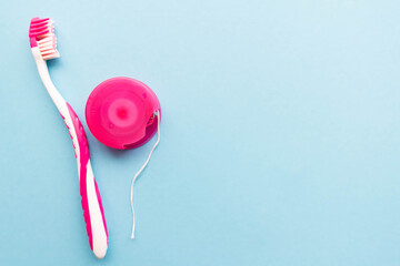 Image of dental floss and a pink toothbrush on light blue backround with a place for text. Medical...