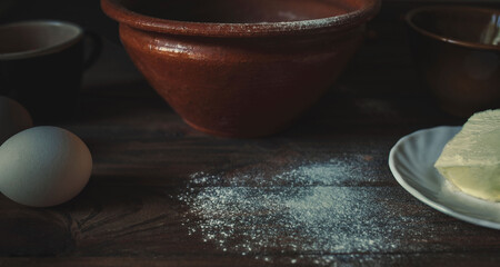 ceramic and earthenware on a dark wooden table with flour butter and egg