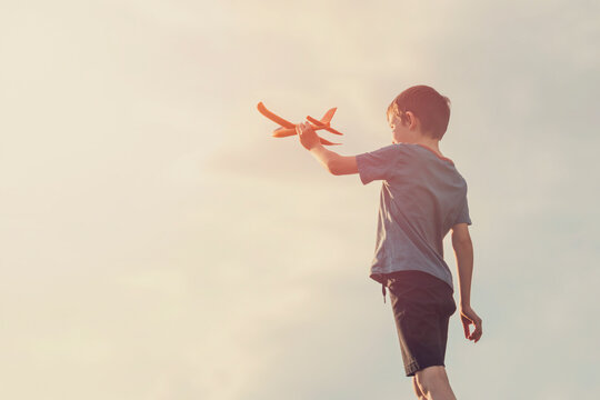 Little boy launches a toy plane into the air. Child launches a toy plane