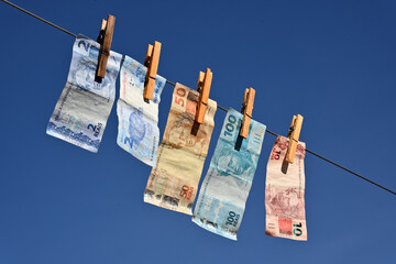 Notas de reais brasileiros secando no varal após serem higienizados	