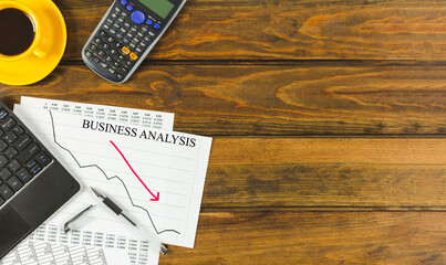Fototapeta premium Business analysis chart with laptop and calculator on a brown wooden table