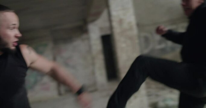 Two angry, muscular men fighting with skilled in an abandoned building