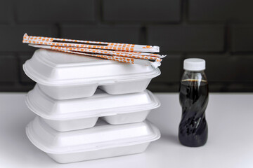 Takeaway concept. Food box with sushi and rolls, soy sauce and chopsticks.