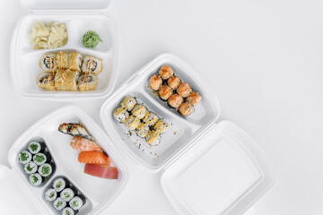 Set of rolls and sushi in a plastic box open space, top view. Delivery service.