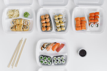 Assorted sushi and rolls mix in a plastic box (top view). Delivery service consept.