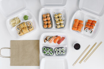  Sushi and rolls in a plastic box and paper bag (top view). Delivery service consept.