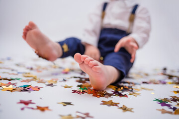 Small feet of a boy close up with confetti on a white isolated background