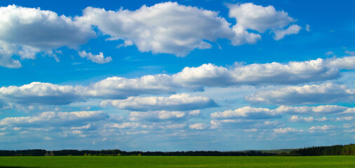 Green grass field and blue sky with white clouds,panoramic view.