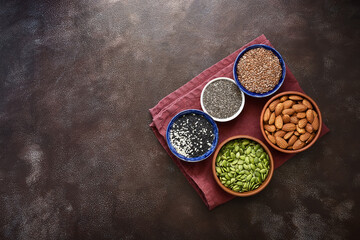Various seeds in a bowl on a dark rustic background. A set of seed: sesame, flax, chia, pumpkin, almonds. Top view, copy space.
